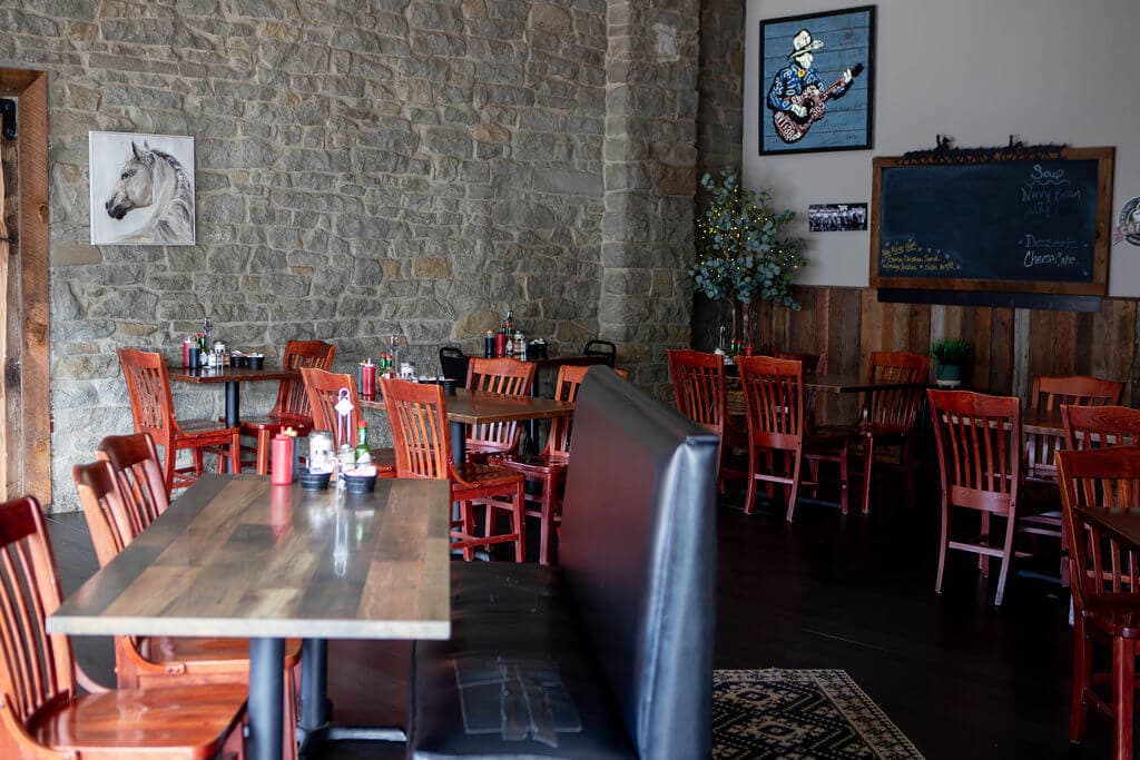 Dining room tables and red wooden chairs along the cafe's original sandstone wall, with a horse painting and the daily specials chalkboard