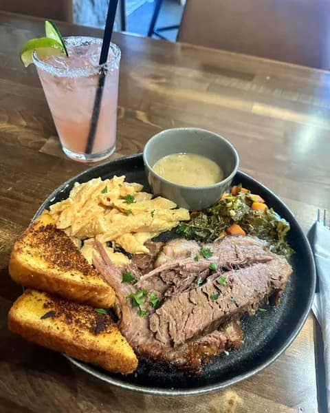 A sliced prime rib dinner with sides and grilled bread