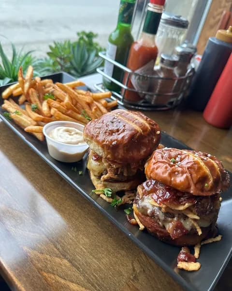 Two glazed burger sliders with crispy onions and a side of fries