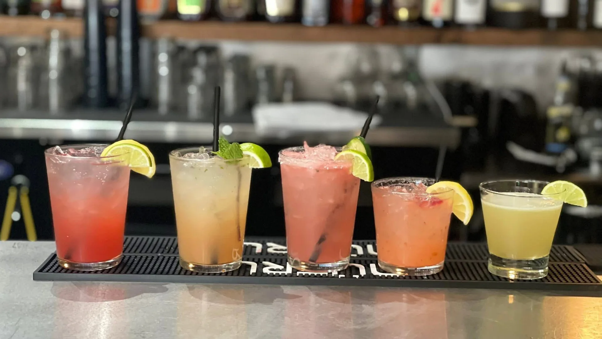 Five colorful craft cocktails lined up across the Quarry Bar